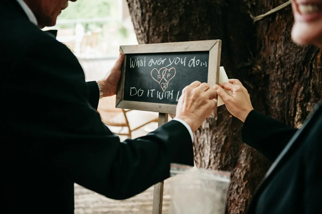 Astrid und Peter mit einer handgeschriebenen Tafel bei ihrer Hochzeit in Goldegg