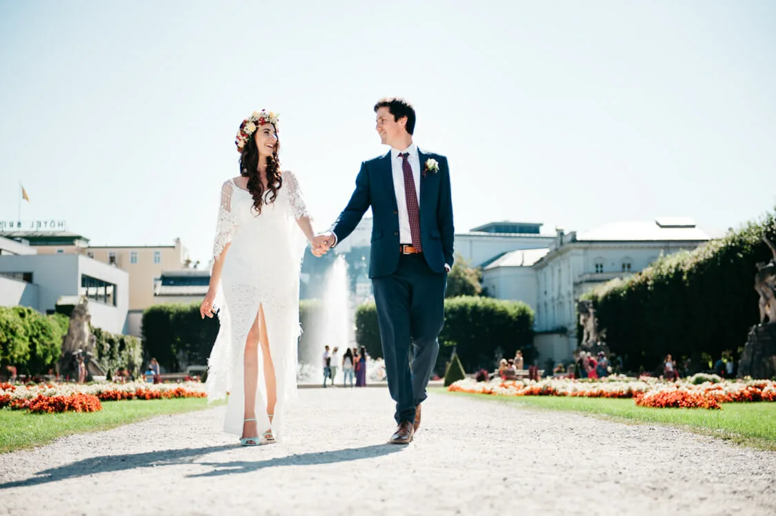 Emily und John gehen Hand in Hand durch den Mirabellgarten in Salzburg
